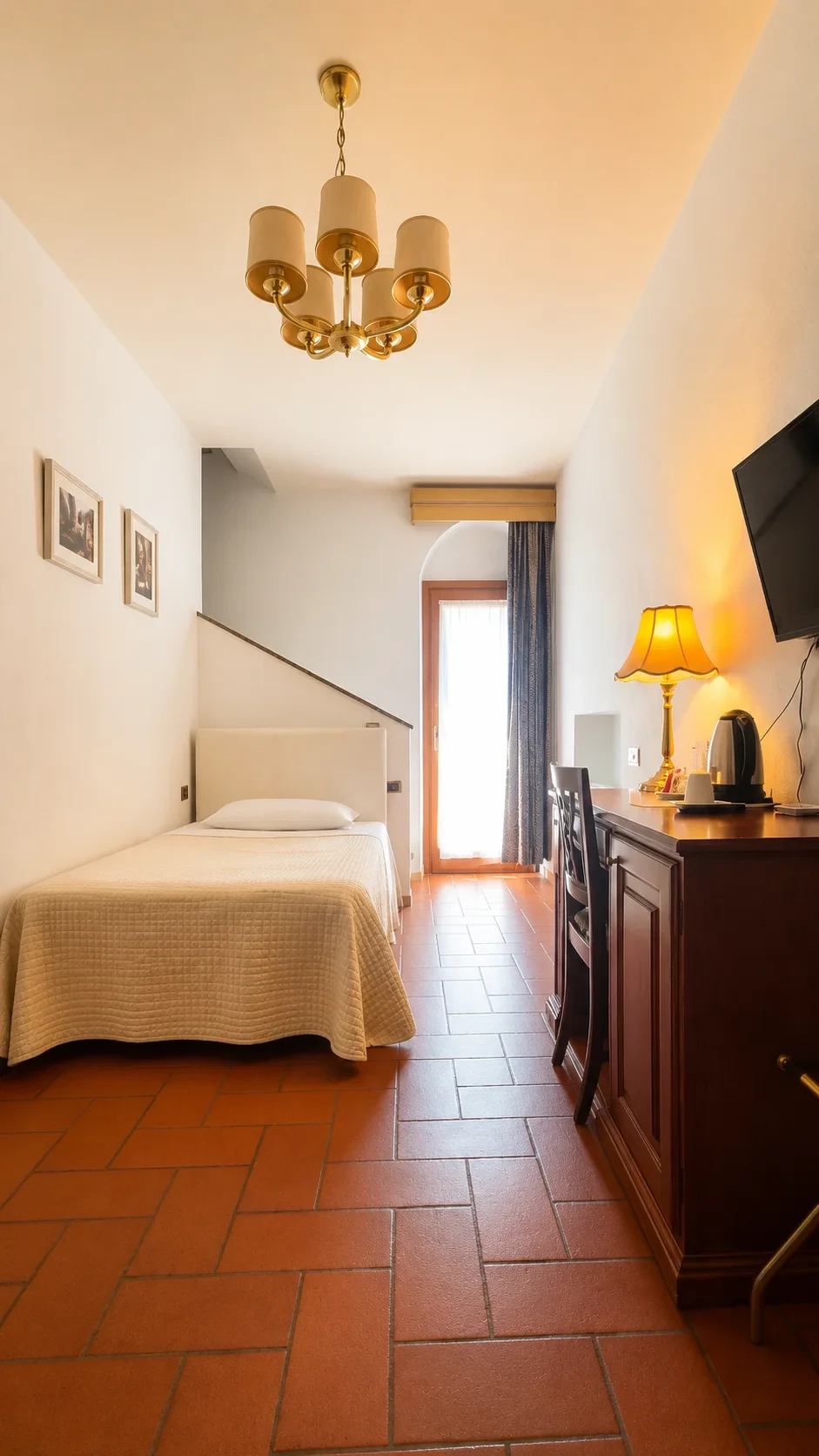 La Camera singola 404 Nete con letto, scrittoio in legno, pavimento in cotto e portafinestra illuminata dalla luce naturale