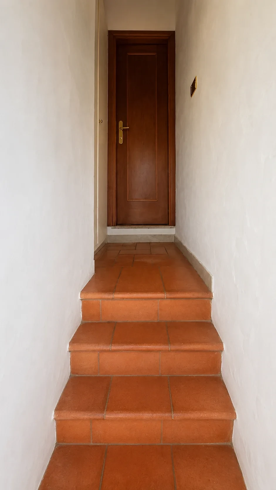 La breve scala interna in cotto della Camera 404 che conduce alla porta del bagno privato