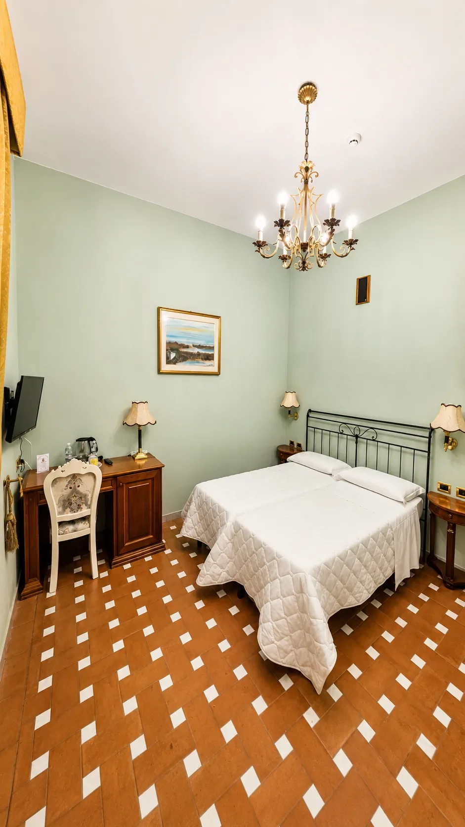 La Camera Twin 316 Aletheia con due letti singoli, pareti verde pastello, scrittoio in legno e lampadario dorato